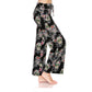 A person models Leggings Depot’s Buttery Soft Print Pajama Pants with a colorful sugar skulls design and an elastic waistband, standing barefoot against a white backdrop.