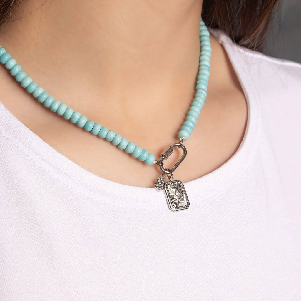 A person wearing a white shirt and the WJW Stainless Steel Turquoise Chunky Bead Carabiner Necklace, featuring a silver rectangular pendant and carabiner clasp detail.