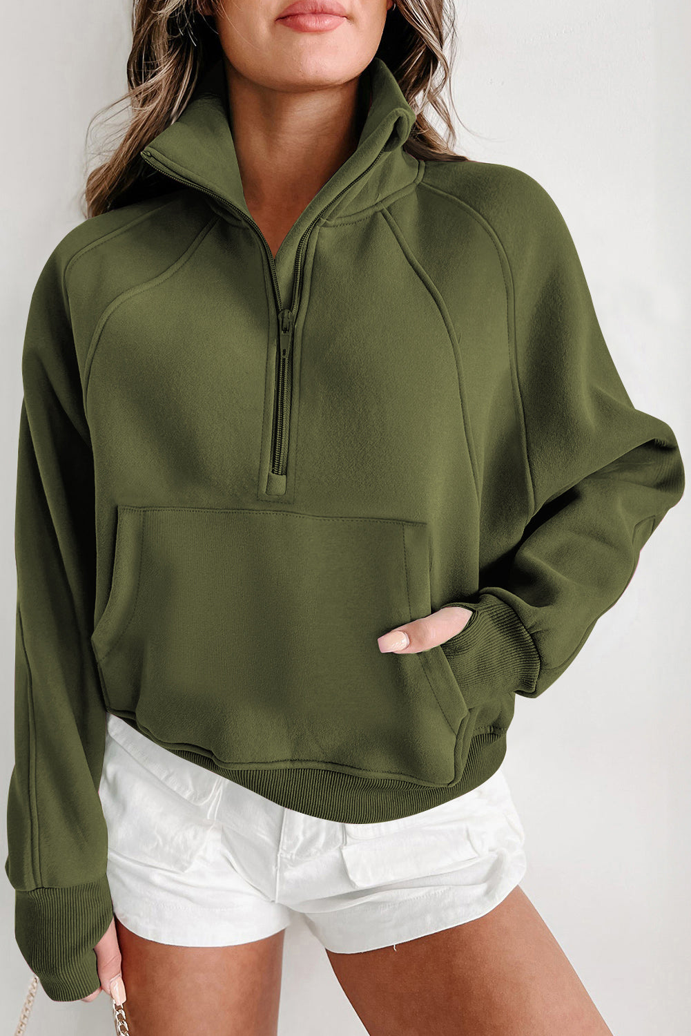 A person wears a gray, zip-up stand collar sweatshirt with ribbed thumbhole sleeves from Shewin, paired with white shorts.