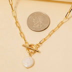 The Anarchy Street Toggle Chain Link Disc Pearl Charm Necklace is displayed beside a quarter for size comparison.
