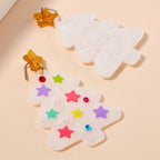 Add a festive touch to your holiday look with the Lilla Haven Glittery Christmas Tree Drop Earrings. This playful pair features two marbled white, acrylic tree-shaped earrings—one adorned with colorful stars and gems and the other left simple for contrast. Each is topped with a golden star, making these Holiday Acrylic Earrings a sparkling statement piece for any seasonal ensemble.