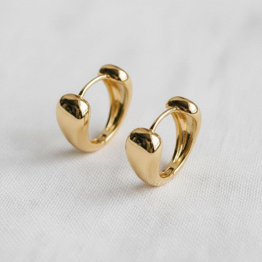 A pair of Contemporary Geometric Drop Earrings by Ellemadera, featuring a small gold heart-shaped hoop design displayed on a white fabric surface—perfect for adding a touch of modern jewelry style to any look.