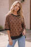 A woman wearing a Kori America Mocha Polka Dot Oversized Top featuring a black crew neck and matching sleeve cuffs.
