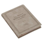 A beige faux leather hardcover book titled “Devotional 10 Minutes with God for Women” by Christian Art Gifts is displayed lying on a white surface.