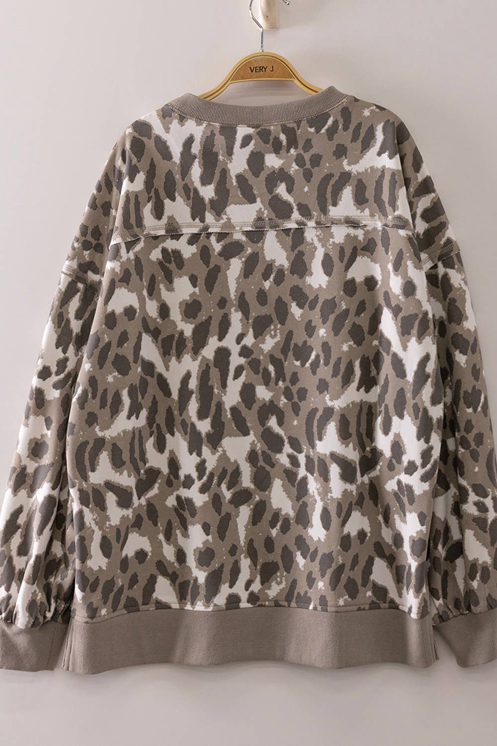 The very J Leopard Printed Crew Neck Sweatshirt, featuring a relaxed fit and a brown, beige, and white leopard print pattern, is displayed on a hanger against a plain background.