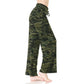 A person stands barefoot against a plain white background wearing Leggings Depot Buttery Soft Print Pajama Pants in a loose-fitting green camouflage pattern with an elastic waistband.
