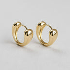 The Contemporary Geometric Drop Earrings by Ellemadera feature a modern, chunky gold design with smooth, rounded shapes and are showcased against a light neutral background.