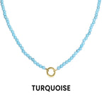 A Semi Precious Natural Stone Charm Keeper Necklace by WJW, featuring turquoise beads and an elegant 18K Gold PVD coated circular clasp, is displayed against a white background with the word "TURQUOISE" written below.