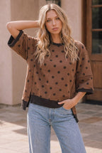 A woman wearing a Mocha Polka Dot Oversized Top in mocha with dark trim, paired with light blue jeans.