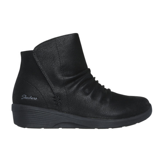 The Arya Ankle Boot in Black by SKECHERS USA INC features a vegan-friendly design with a textured surface, side ruching, and a wedge heel, enhanced with an Air-Cooled Memory Foam® cushioned insole for lasting comfort throughout the day.