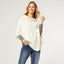 A woman models the COCO + CARMEN Lightweight Ponchos Wrap over a gray long-sleeve shirt and blue jeans, smiling against a plain light background—ideal for layering your wardrobe.
