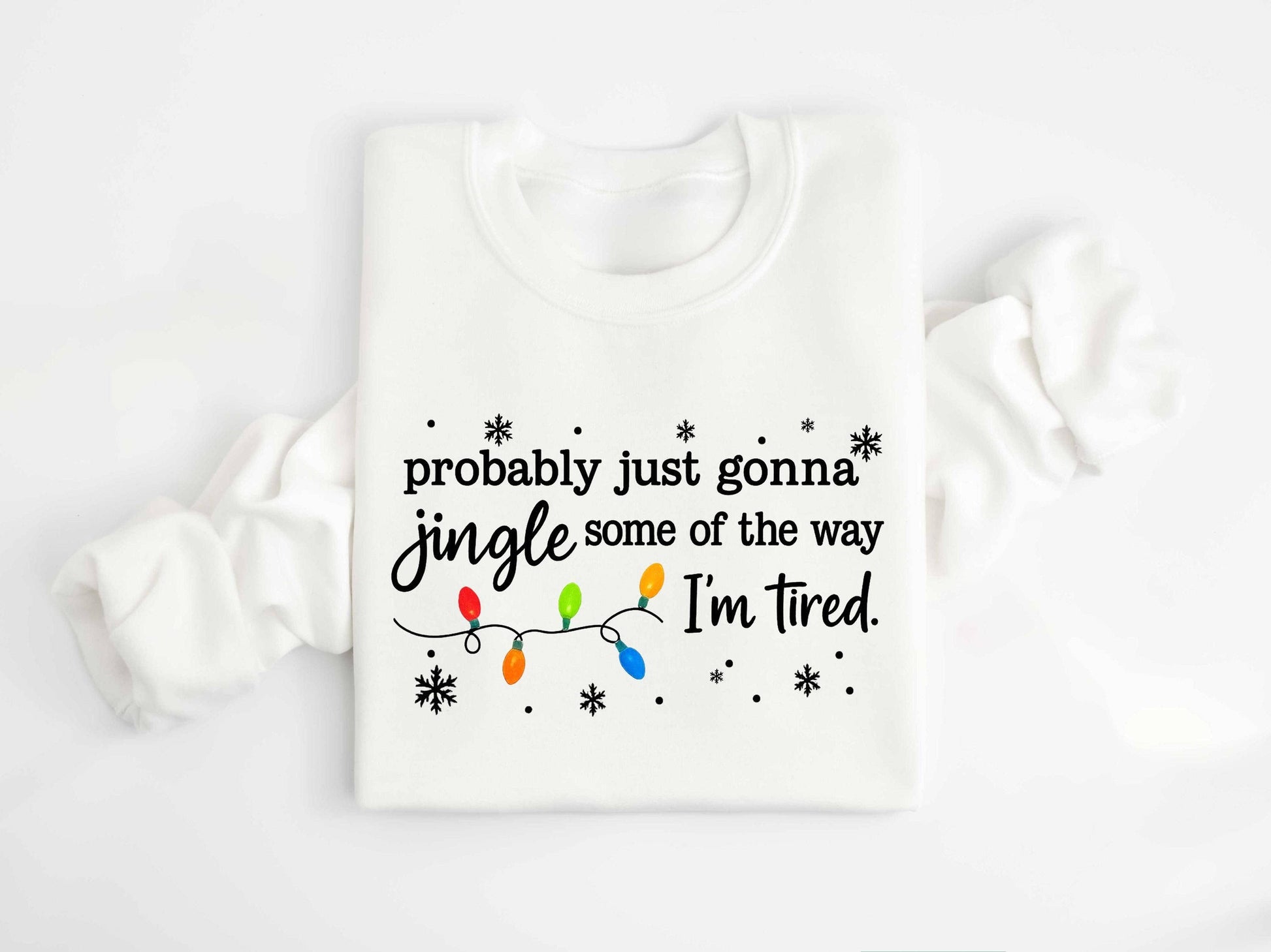 TheKingShirt’s Jingle All the Way Christmas Long Sleeve Shirt features festive Christmas lights and snowflakes, plus the humorous line: "probably just gonna jingle some of the way I'm tired," on a super soft sweatshirt.