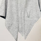 JC Sunny Fashion's Cashmere-Blend Knit Triangle Shawl features a light gray, textured finish, cross-front design, pointed hem, and single pocket, shown against a plain background.