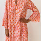 A woman in a Shewin Orange Floral Button V Neck Bell Sleeve Mini Dress stands against a plain white background.