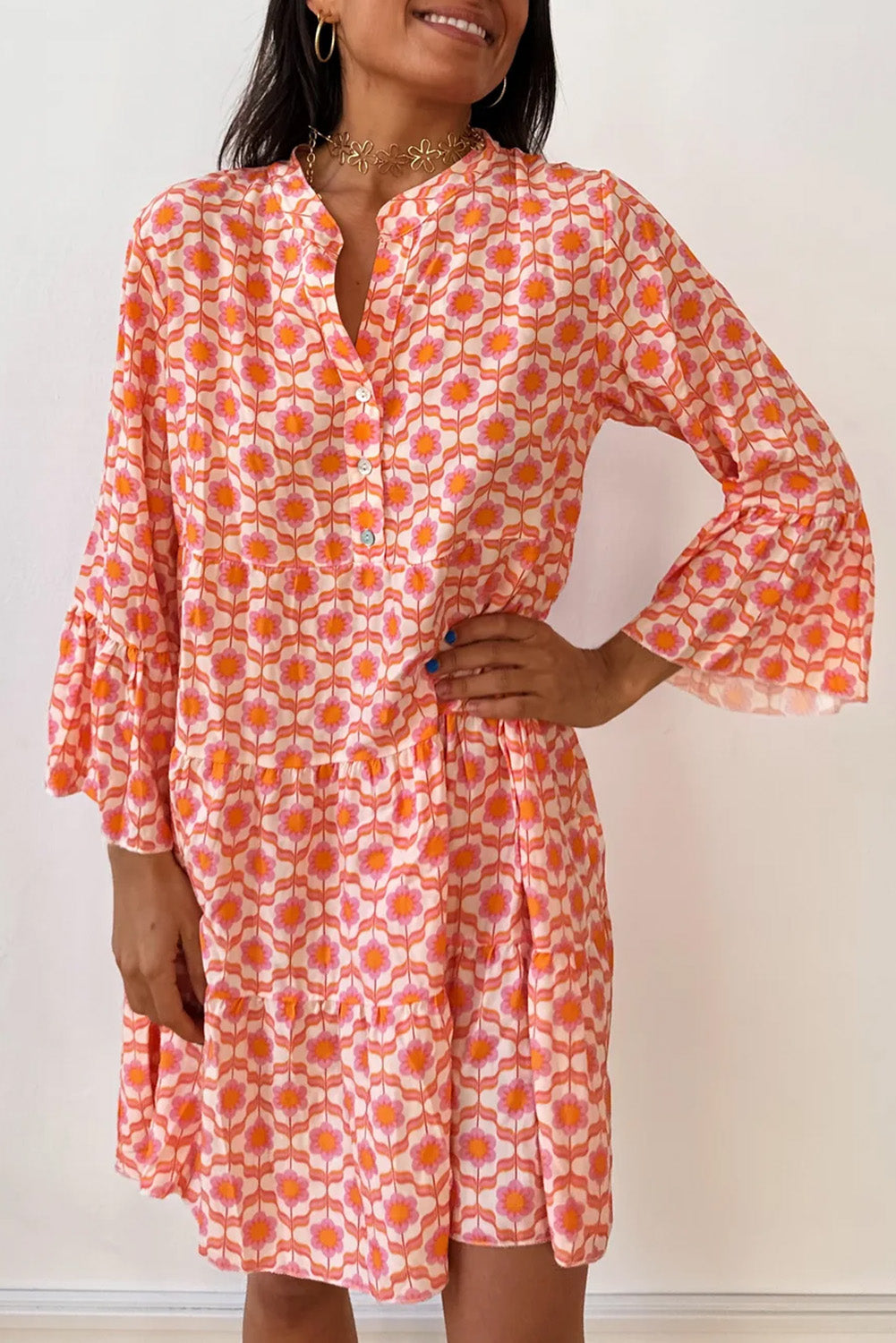 A woman in a Shewin Orange Floral Button V Neck Bell Sleeve Mini Dress stands against a plain white background.