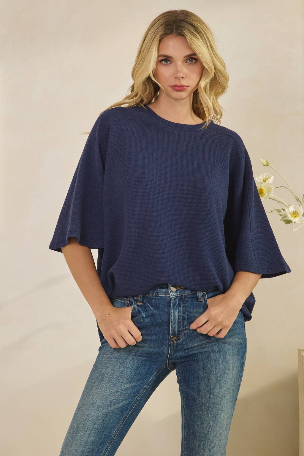 Woman wearing a navy blue CLOUDY KNIT 3/4 SLEEVE ROUND NECK TOP with three-quarter length wide sleeves and blue jeans.