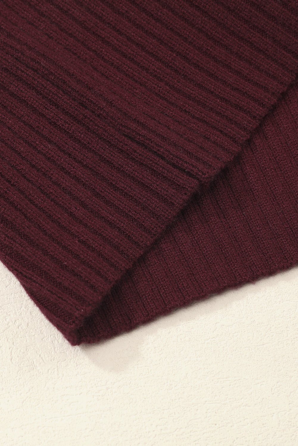 Close-up of a section of the Patch Pocket Ribbed Knit Short Sleeve Sweater by Shewin, featuring dark red ribbing on a light surface and perfect for transitional weather.