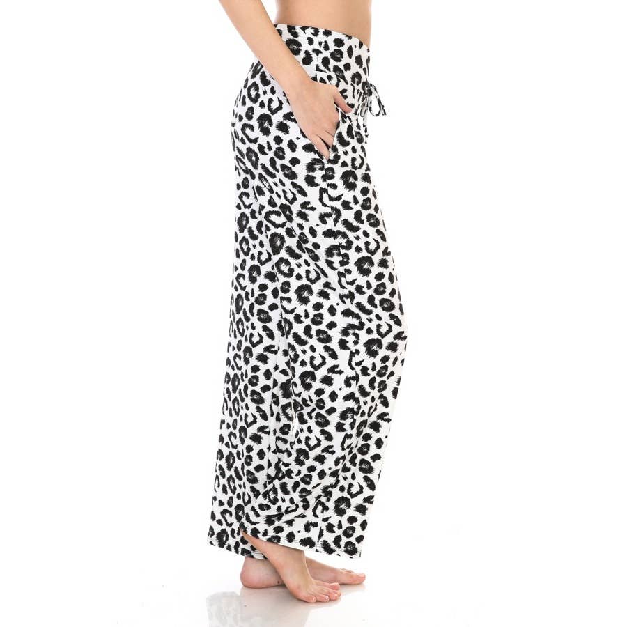 A person stands barefoot in Leggings Depot Buttery Soft Print Pajama Pants, featuring a high waist, wide-leg fit, elastic waistband, and a chic black and white leopard print.