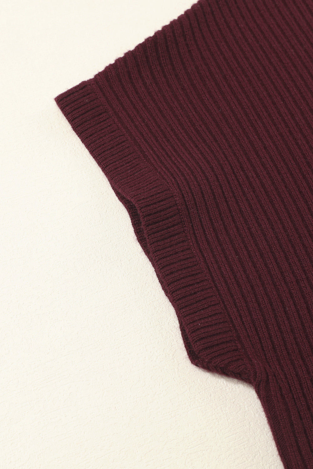 Close-up of Shewin’s burgundy Patch Pocket Ribbed Knit Short Sleeve Sweater fabric, folded at an angle on a light background; perfect for casual style in transitional weather.