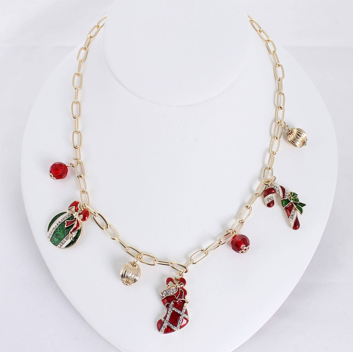 Seasons Jewelry’s Vintage Christmas Charm Necklace showcases vintage-style charms—stocking, candy cane, ornament—accented with red and gold beads, all elegantly presented on a white bust.