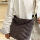 A person carries the 42POPS Corduroy Tote Bag With Guitar Shoulder Strap, paired with a white oversized shirt and gray skirt.