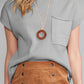 A person wearing a Shewin Patch Pocket Ribbed Knit Short Sleeve Sweater paired with a pendant necklace and a brown buttoned skirt.