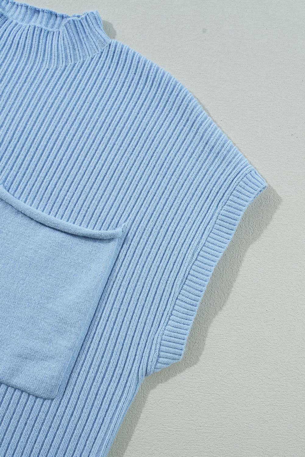 Flat lay of the Shewin Patch Pocket Ribbed Knit Short Sleeve Sweater in light blue. Featuring a chest pocket, this stylish and comfortable sweater is perfect for transitional weather.