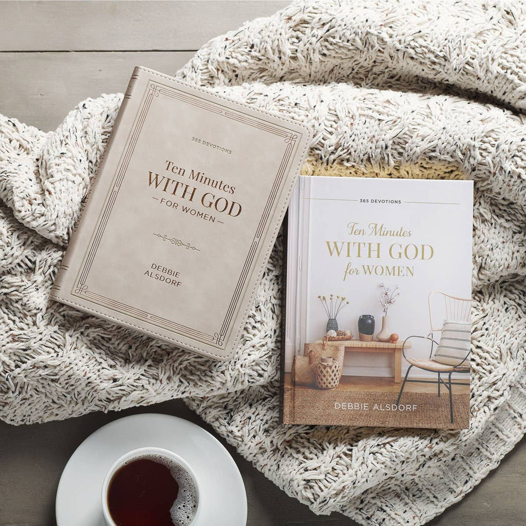 Two copies of the Devotional 10 Minutes with God for Women Faux Leather by Christian Art Gifts rest on a knitted blanket beside a cup of coffee on a wooden surface.