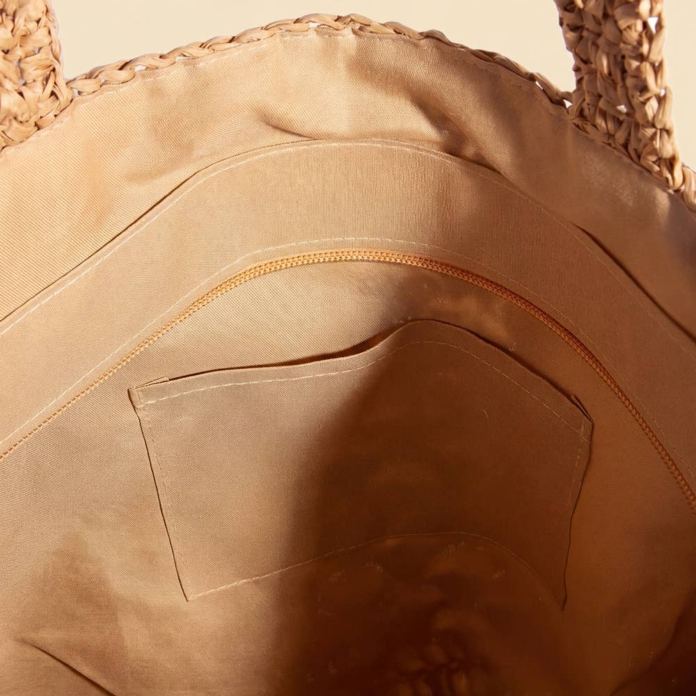 Close-up of the interior of the Anarchy Street Large Woven Straw Fan Stitch Shoulder Tote Bag, featuring a zippered pocket and an open pocket stitched onto a light tan fabric lining.