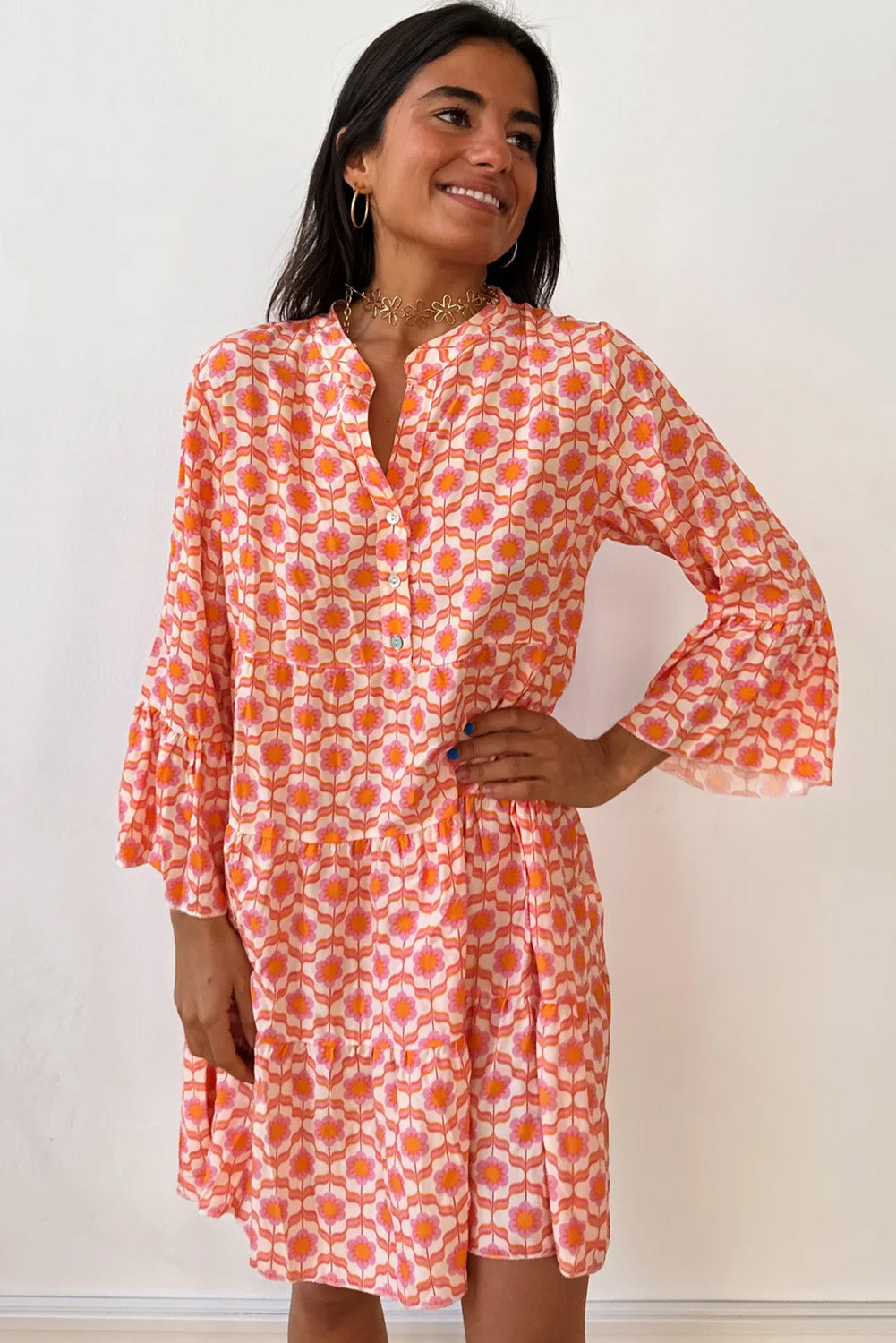 A person smiles while posing in a Shewin Orange Floral Button V Neck Bell Sleeve Mini Dress against a plain white background.