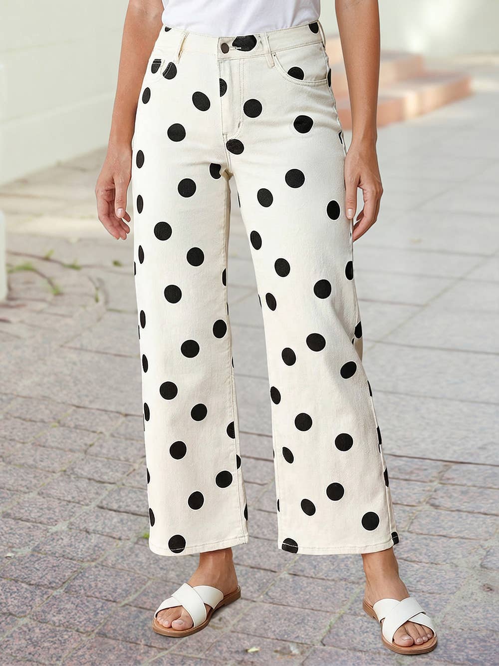 A person models the 1 the Woman Polka Dot Print Straight Leg Casual Pants with a white top and sandals, posing casually on a paved outdoor walkway.