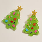 Add festive sparkle to your holiday look with the Glittery Christmas Tree Drop Earrings from Lilla Haven. These holiday acrylic earrings showcase two green Christmas tree shapes crafted from glitter acrylic, embellished with colorful star accents, pearls, rhinestones, and topped with a glittery gold star. Perfect for making a seasonal statement!.