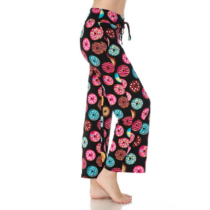 A person stands barefoot in Leggings Depot's Buttery Soft Print Pajama Pants, featuring a colorful donut pattern and comfy elastic waistband, shown from the side against a white background.