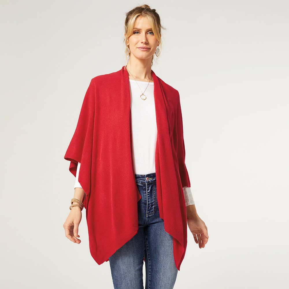A woman wearing the COCO + CARMEN Kiara Lightweight Wrap in red over a white top and blue jeans stands against a plain background. Main image