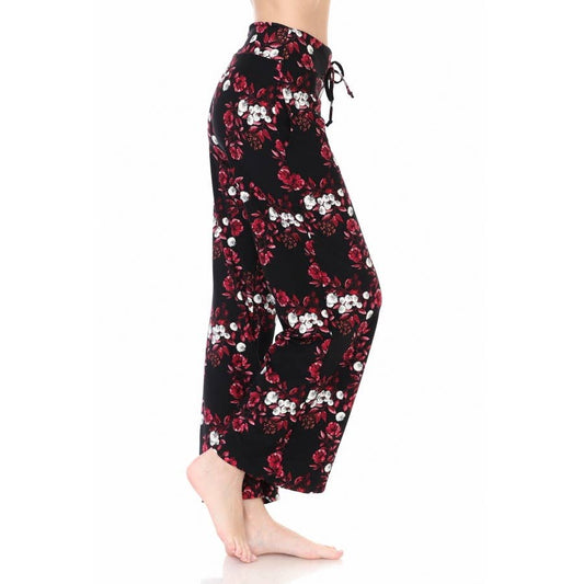 A person models Leggings Depot Buttery Soft Print Pajama Pants with a red floral and white design, high-waisted loose fit, elastic waistband, and drawstring, standing barefoot on a white background.