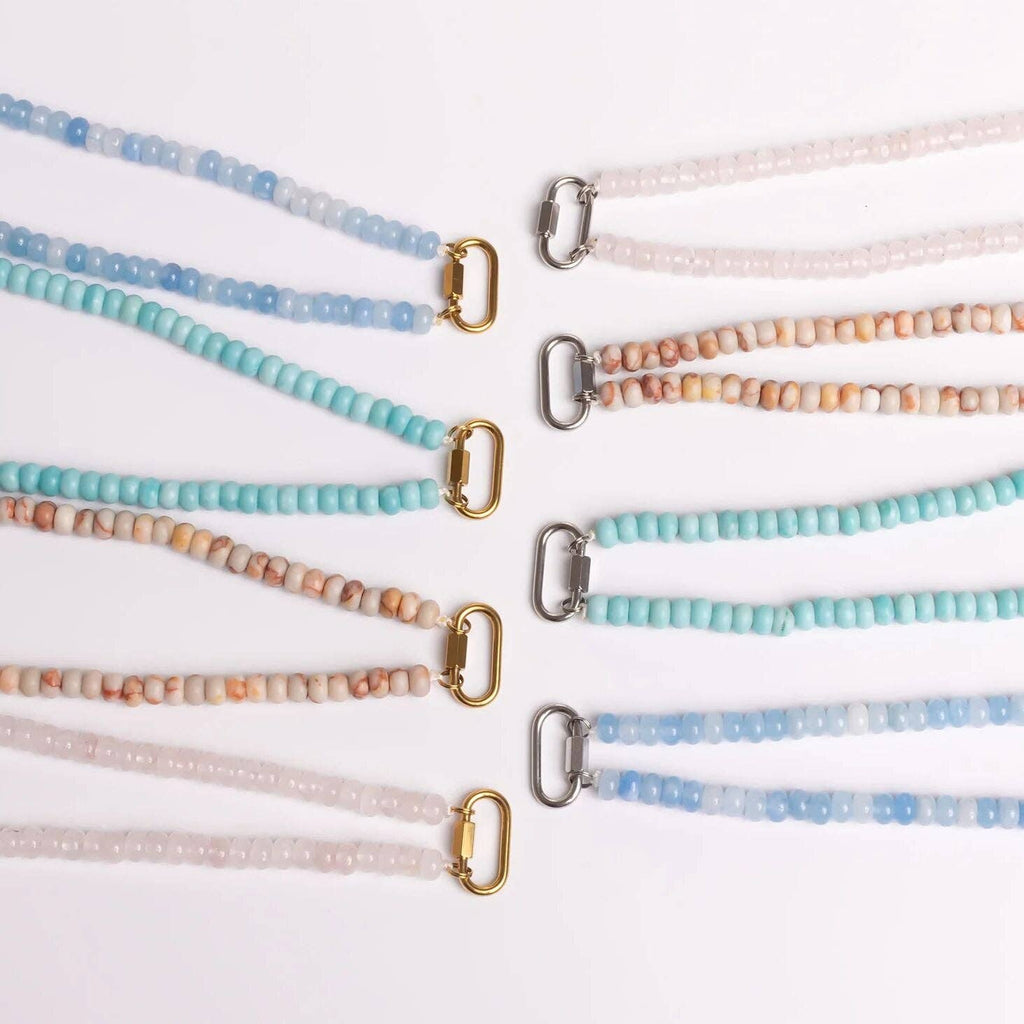 Nine WJW Stainless Steel Chunky Glass Bead Carabiner Necklaces are arranged in rows on a white background. Featuring metal clasps in gold and silver, each necklace showcases chunky glass beads in shades of blue, turquoise, beige, and light pink for a vibrant yet elegant appearance.