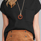 A woman wears a Shewin black ribbed knit short-sleeve sweater with a patch pocket, pairs it with a brown buttoned skirt, and accessorizes with a round pendant necklace, ideal for transitional weather.