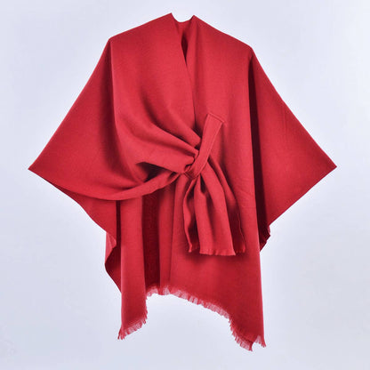 The ACCITY SIMPLE SOLID COLOR OBLIQUE STRAP CAPE SHAWL, shown in red with a knotted front and fringed edges against a white background, is the ideal layering piece for any outfit.