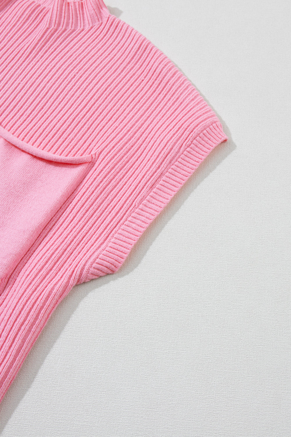 Close-up of a Shewin Pink Patch Pocket Ribbed Knit Short Sleeve Sweater, made from soft knit fabric with a handy pocket, ideal for versatile wear in transitional weather. Photographed against a light gray background.