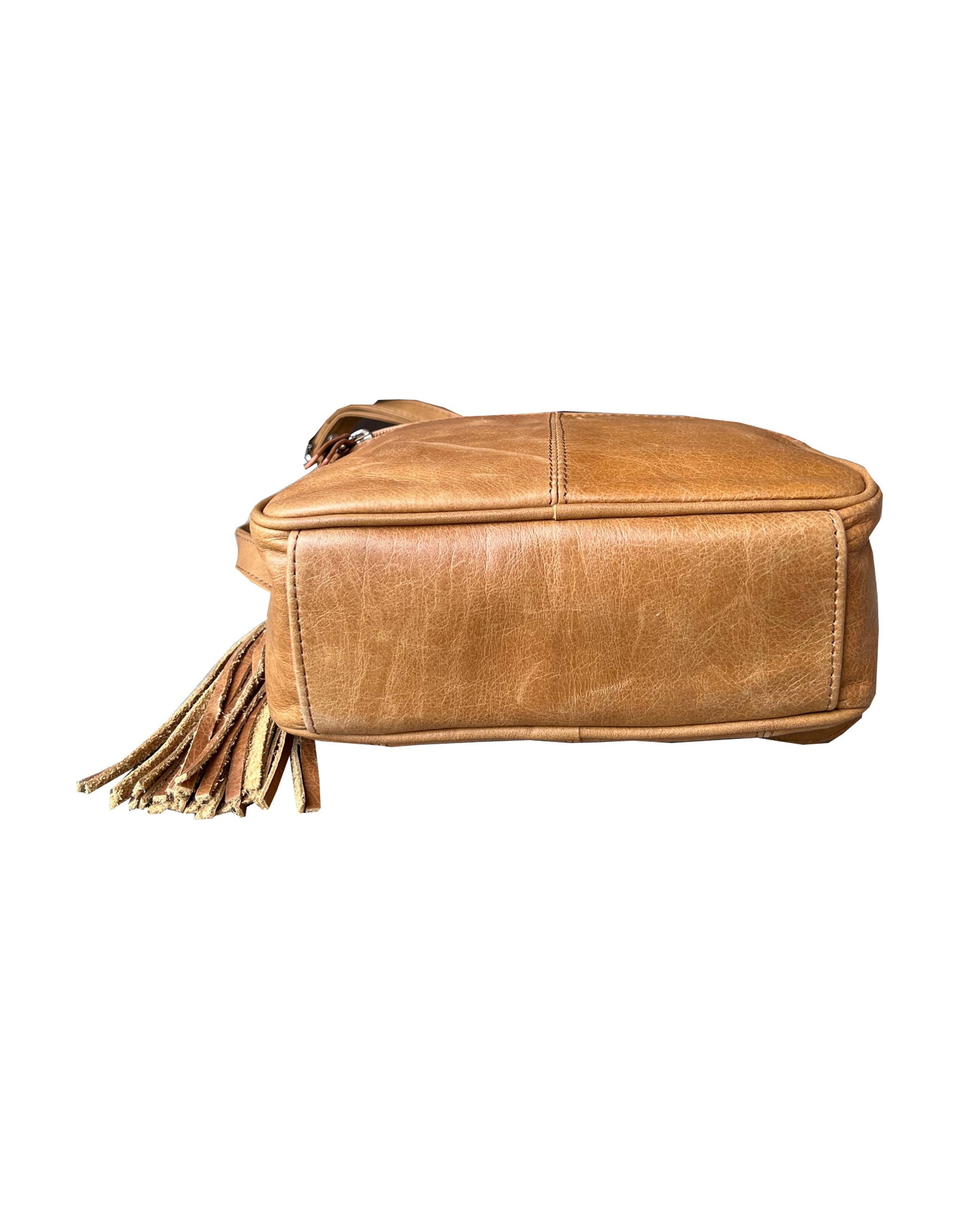 The Roma Leathers, Inc. Cowhide Leather Crossbody is a tan cowhide bag with a tassel, shown from the bottom on a white background, and features an adjustable shoulder strap for comfort and versatility.