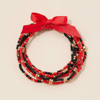 Game Day Seed Beaded Bracelet Set consisting of red, black, and gold seed bead stretch bracelets tied together with a red ribbon bow.