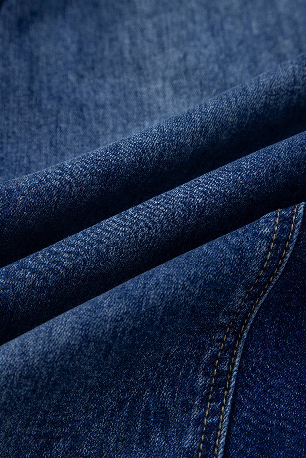 Close-up of dark blue denim with visible stitching and texture, highlighting details of the 1 the Woman Drawstring Seam Detail Raw Hem Wide Leg Denim Pants.