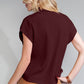 A person with blonde hair is wearing the maroon Shewin Patch Pocket Ribbed Knit Short Sleeve Sweater and brown pants, viewed from the back against a gray background. This stylish and comfortable outfit is perfect for transitional weather.