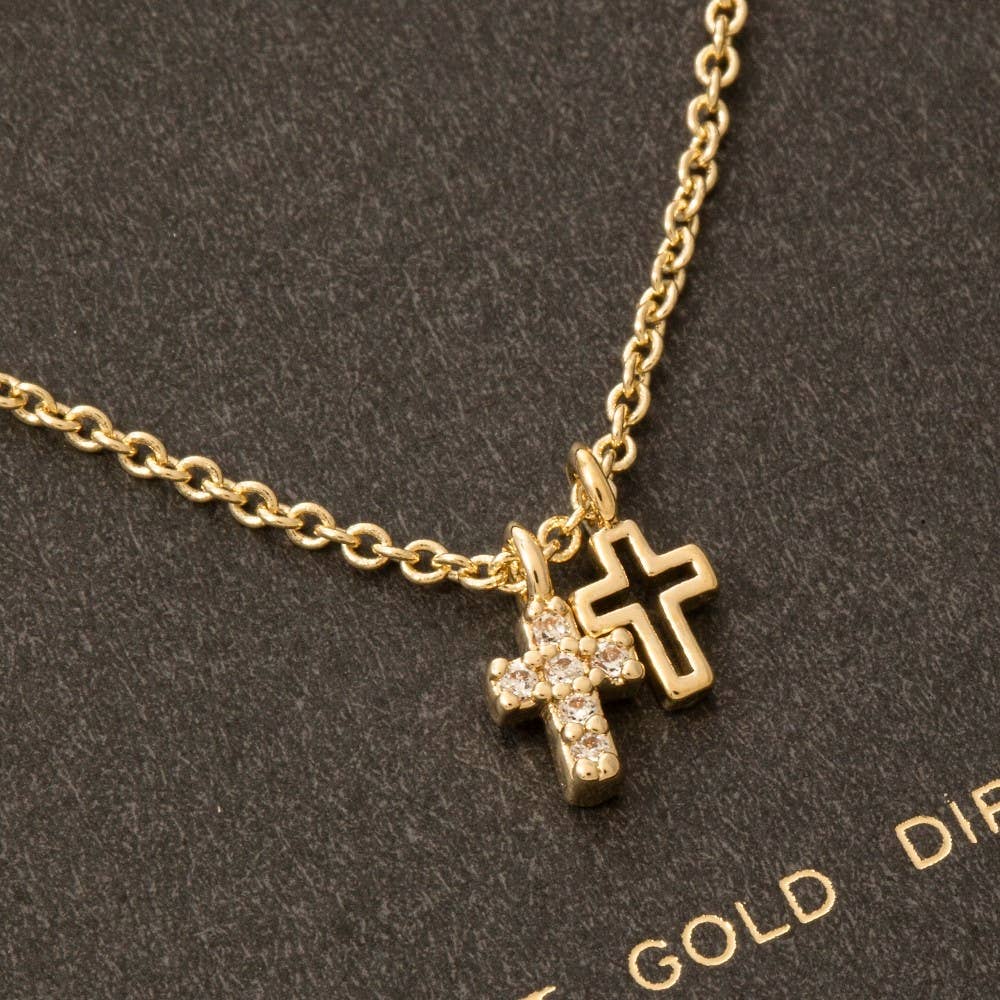 The Anarchy Street Secret Box Gold Dipped Cz Cross Pendant Necklace showcases two cross pendants—one plain, one sparkling with cubic zirconia—beautifully displayed against a textured dark background.