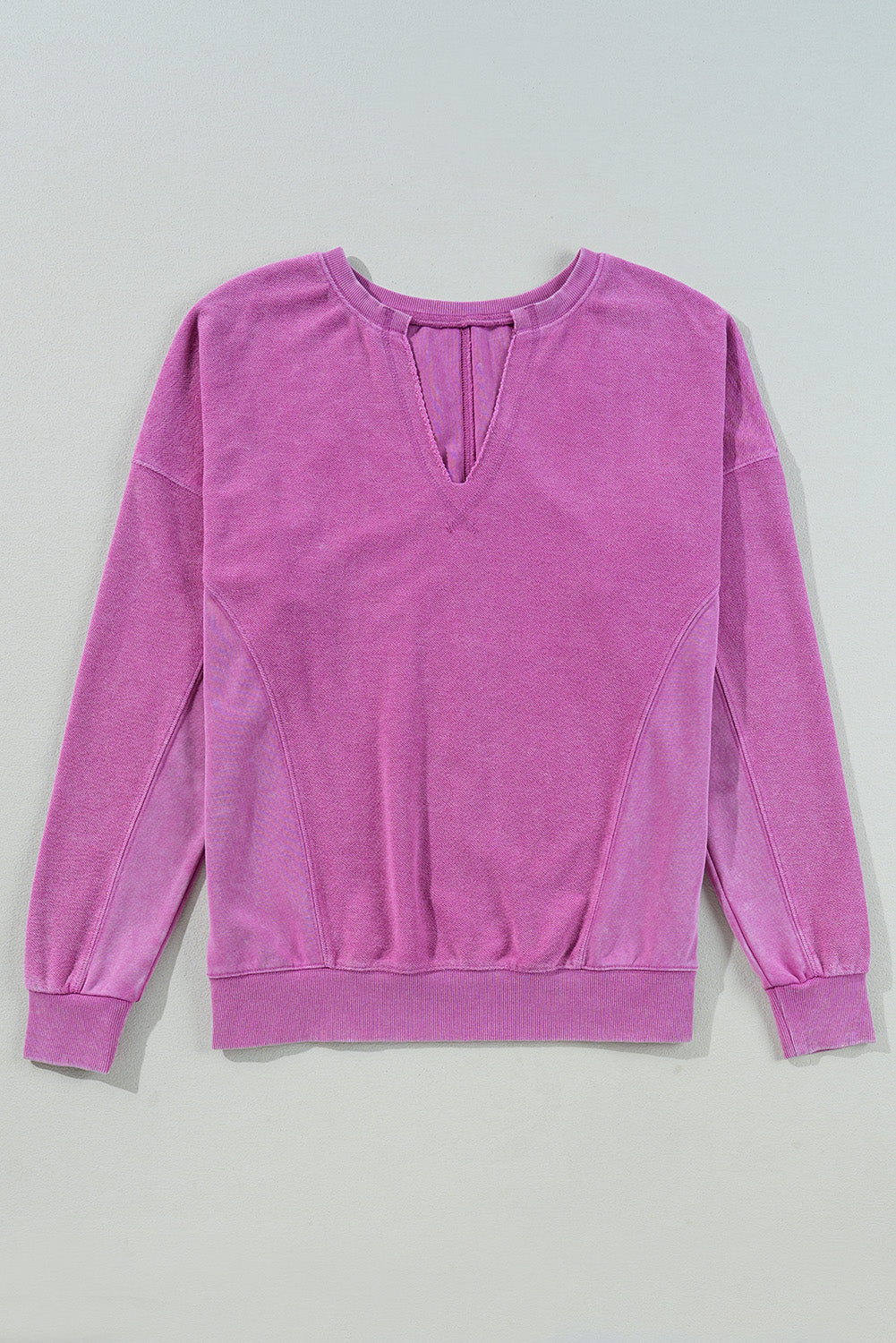 The Shewin Notched Neck Exposed Seam Drop Shoulder Sweatshirt, made from high-quality fabric, is a comfortable long-sleeve purple piece featuring a small v-cut neck detail and laid flat on a light surface.