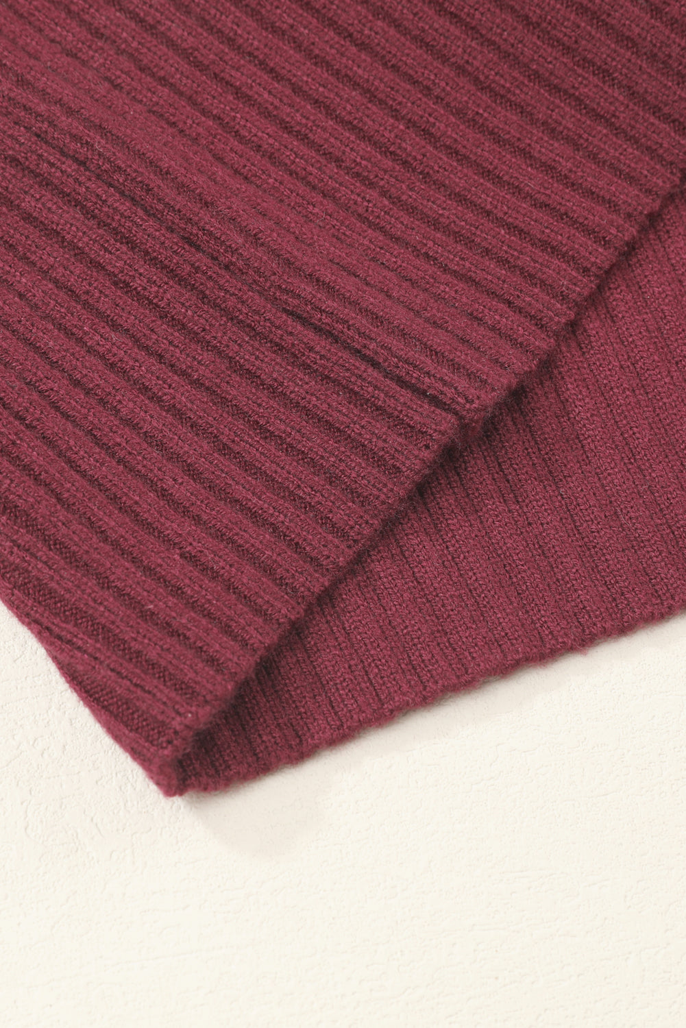 Close-up of a folded maroon Patch Pocket Ribbed Knit Short Sleeve Sweater by Shewin, ideal for a modern casual look, resting on a light surface.