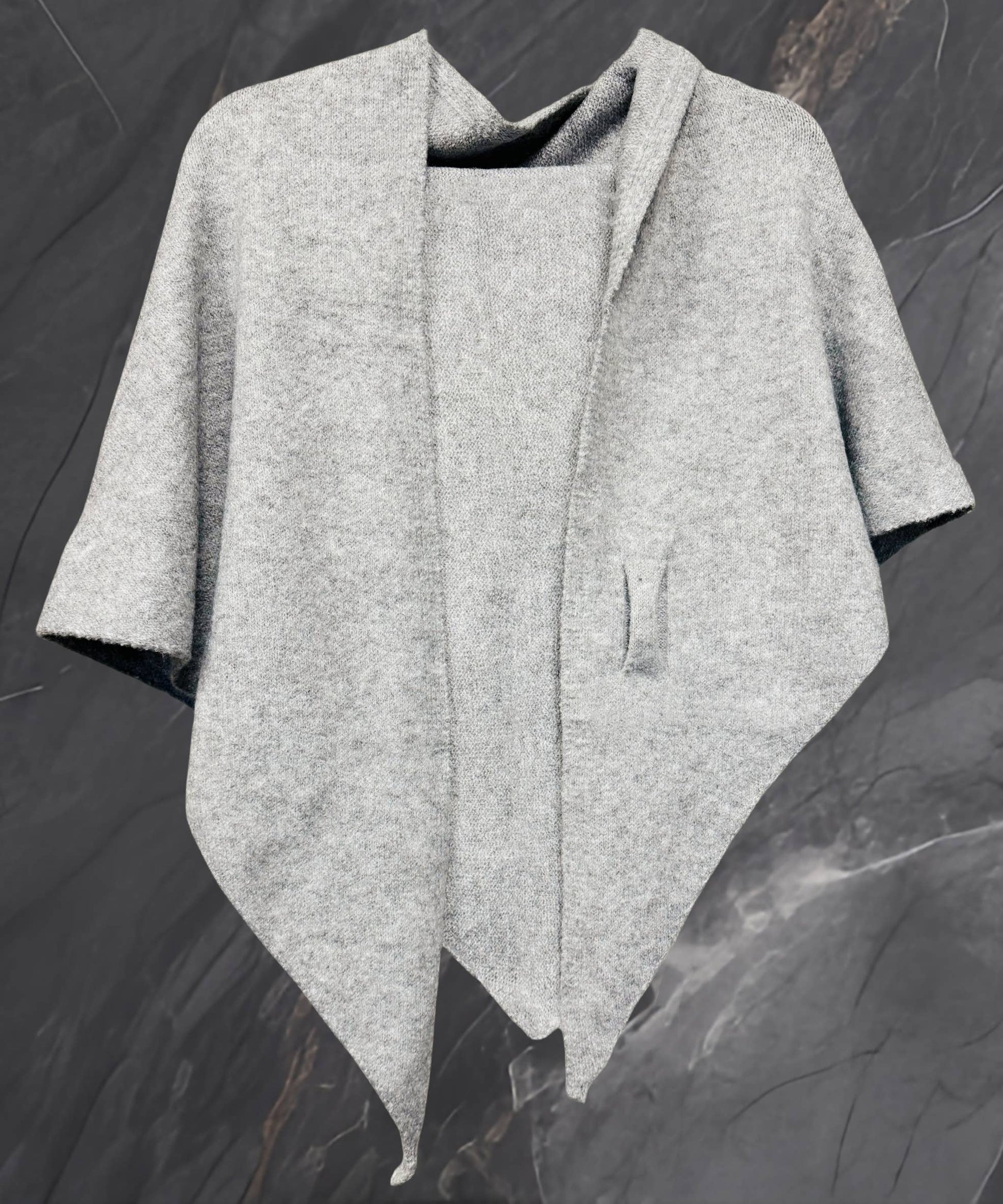 The JC Sunny Fashion Cashmere-Blend Knit Triangle Shawl features a chic cross-front design and drapes stylishly against a dark marble background.