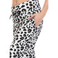 A person wearing Leggings Depot Buttery Soft Print Pajama Pants in black leopard print, shown waist to mid-thigh, with one hand in a side pocket and an elastic waistband for comfort.