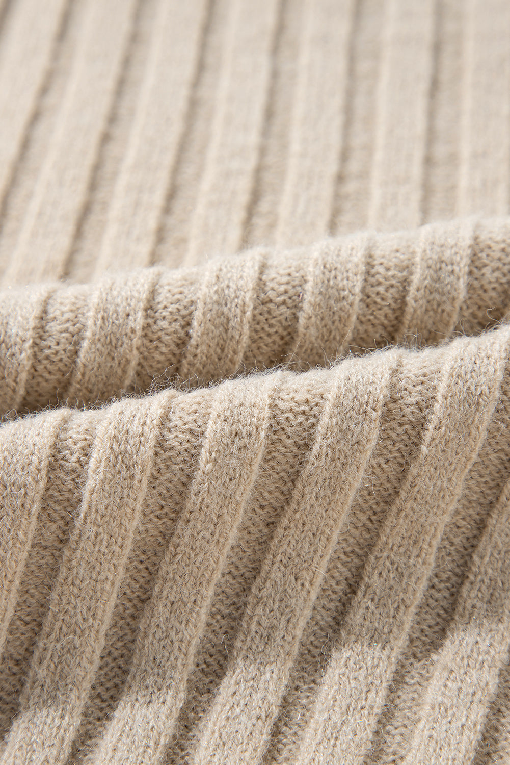 Close-up of the beige ribbed fabric with a textured, wavy pattern showcases rib-knit details similar to Shewin's Khaki Cable Knit Colorblock Crew Neck Drop Shoulder Sweater.