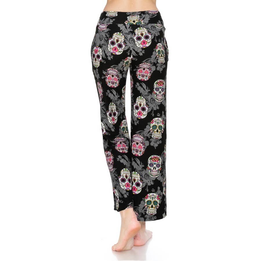 A person stands barefoot, facing away, wearing Leggings Depot Buttery Soft Print Pajama Pants featuring colorful sugar skulls and a comfy elastic waistband.